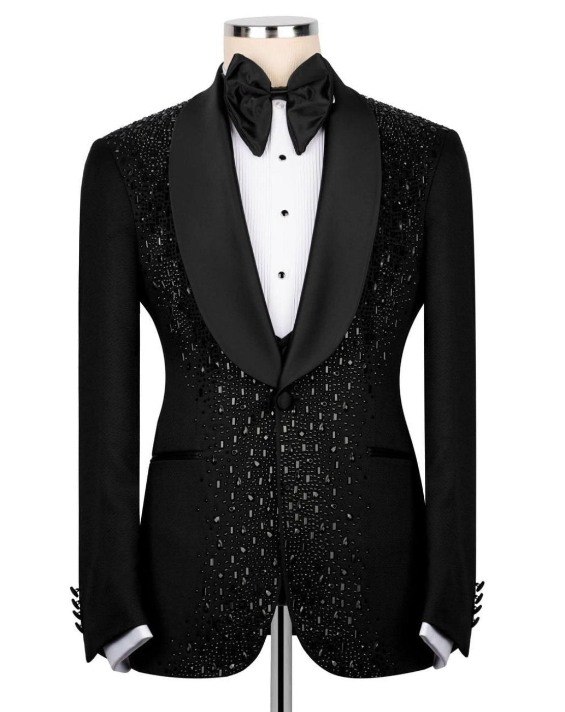 A black tuxedo jacket with sparkling silver beadwork, styled on a mannequin with a black satin bow tie, white dress shirt, and black bow tie.