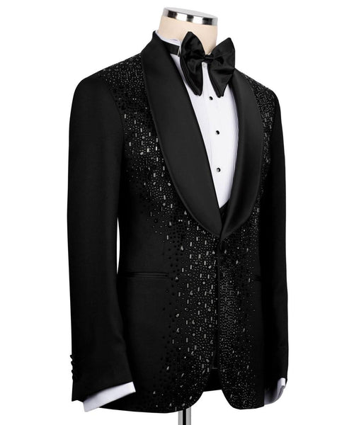 A black tuxedo jacket with a black satin shawl collar and dense silver rhinestone embellishments on the front panel, styled on a mannequin with a white dress shirt and black bow tie against a white background.