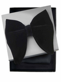 A pre-tied black bow tie presented on a white gift box with a black presentation box underneath, photographed on a plain white background.