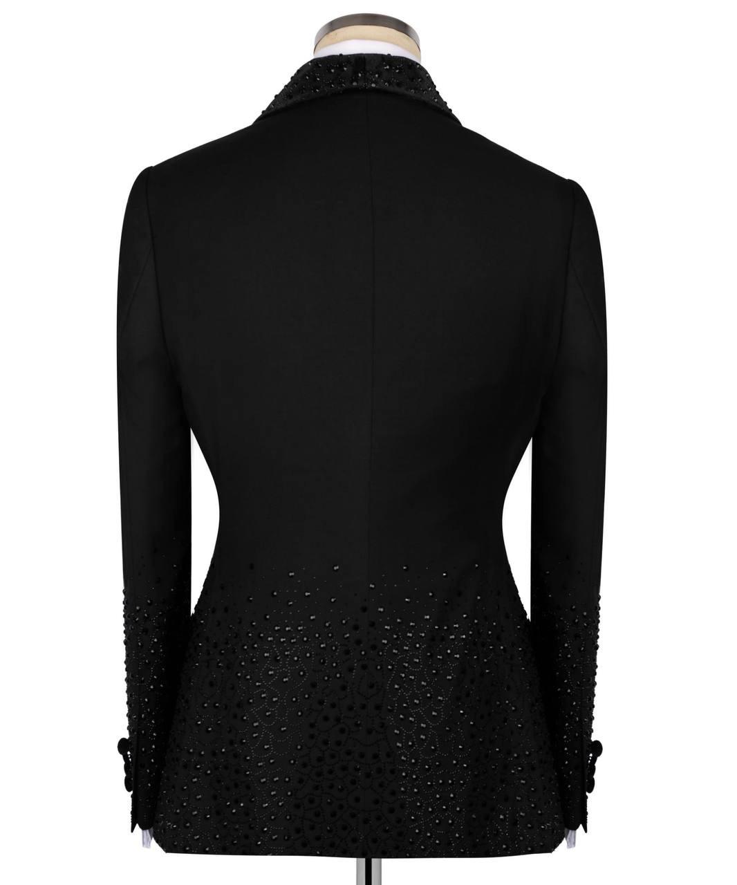 Black long-sleeve blazer shown from the back on a mannequin, featuring a high collar and beaded embellishments along the lower back and cuffs.
