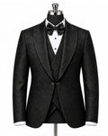 A men's black textured tuxedo jacket with peak lapels, displayed on a mannequin with a matching black vest, white dress shirt, and black bow tie against a white background.