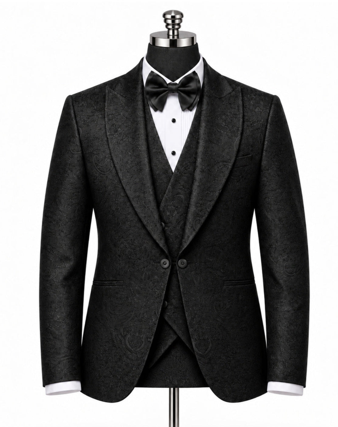 A men's black textured tuxedo jacket with peak lapels, displayed on a mannequin with a matching black vest, white dress shirt, and black bow tie against a white background.