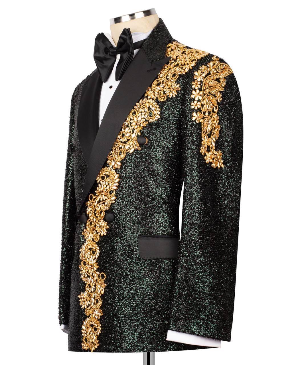 A black sequined tuxedo jacket with ornate gold embroidered detailing on the lapels, displayed on a mannequin with a black bow tie and white dress shirt against a white background.