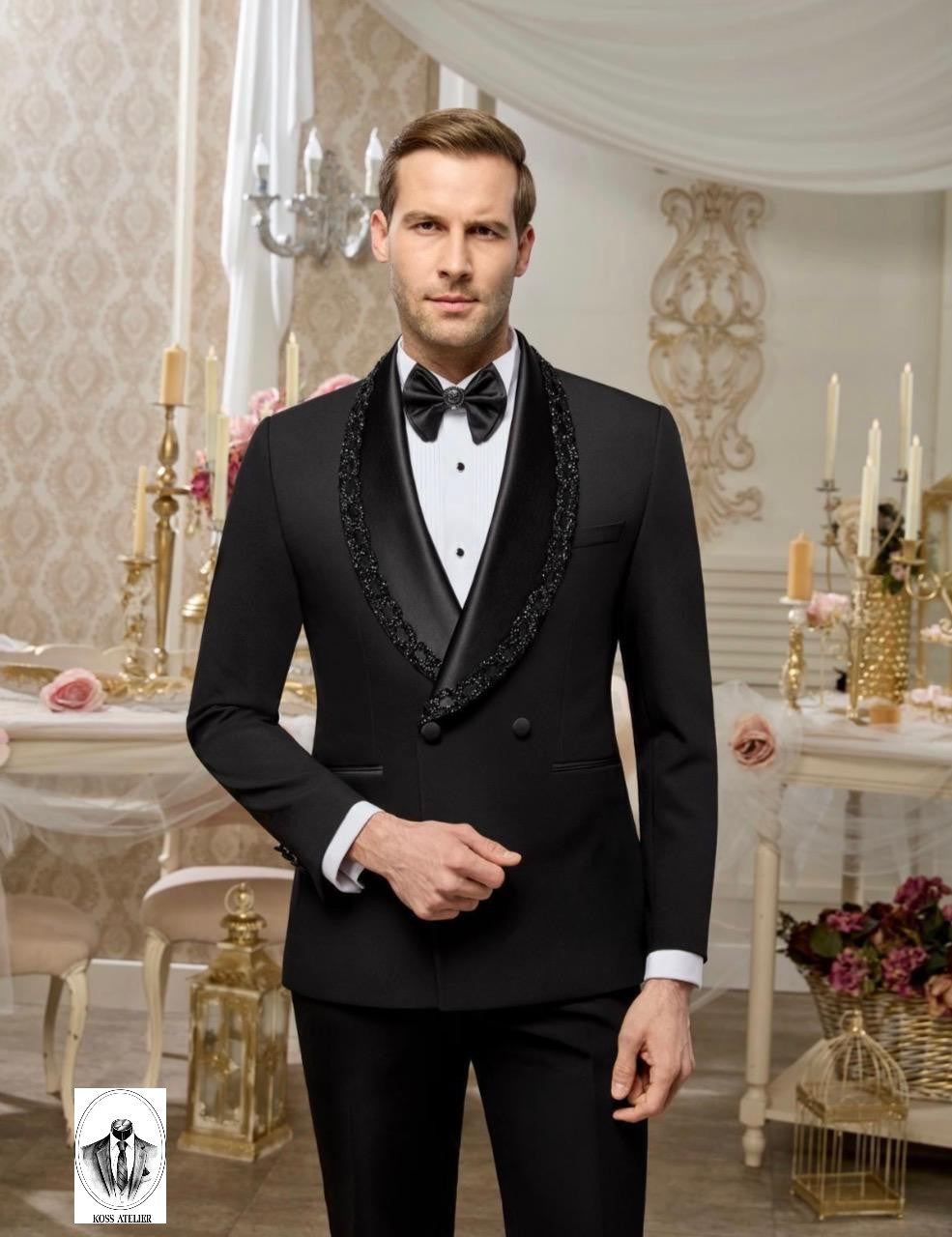 A man wearing a black double-breasted tuxedo jacket with ornate black beaded lapels, a white dress shirt, and a black bow tie, standing in an elegant, vintage-style room decorated with candelabras and drapery.
