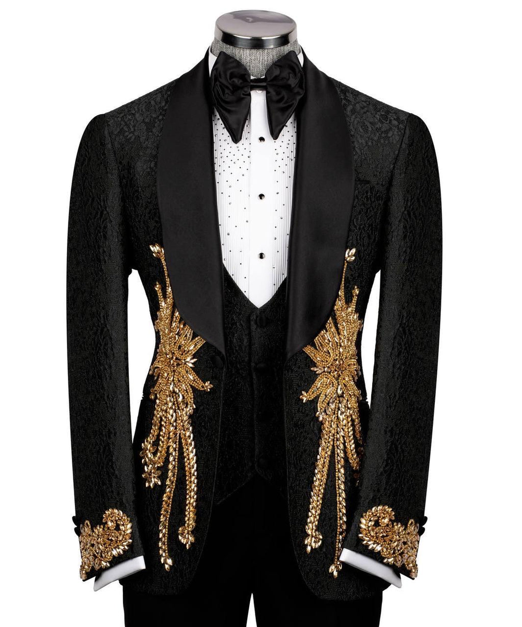 A black tuxedo jacket with ornate gold embroidered leaf motifs and draped gold chain details on the front, displayed on a mannequin with a white polka-dot shirt, black bow tie, and black vest against a plain white background.