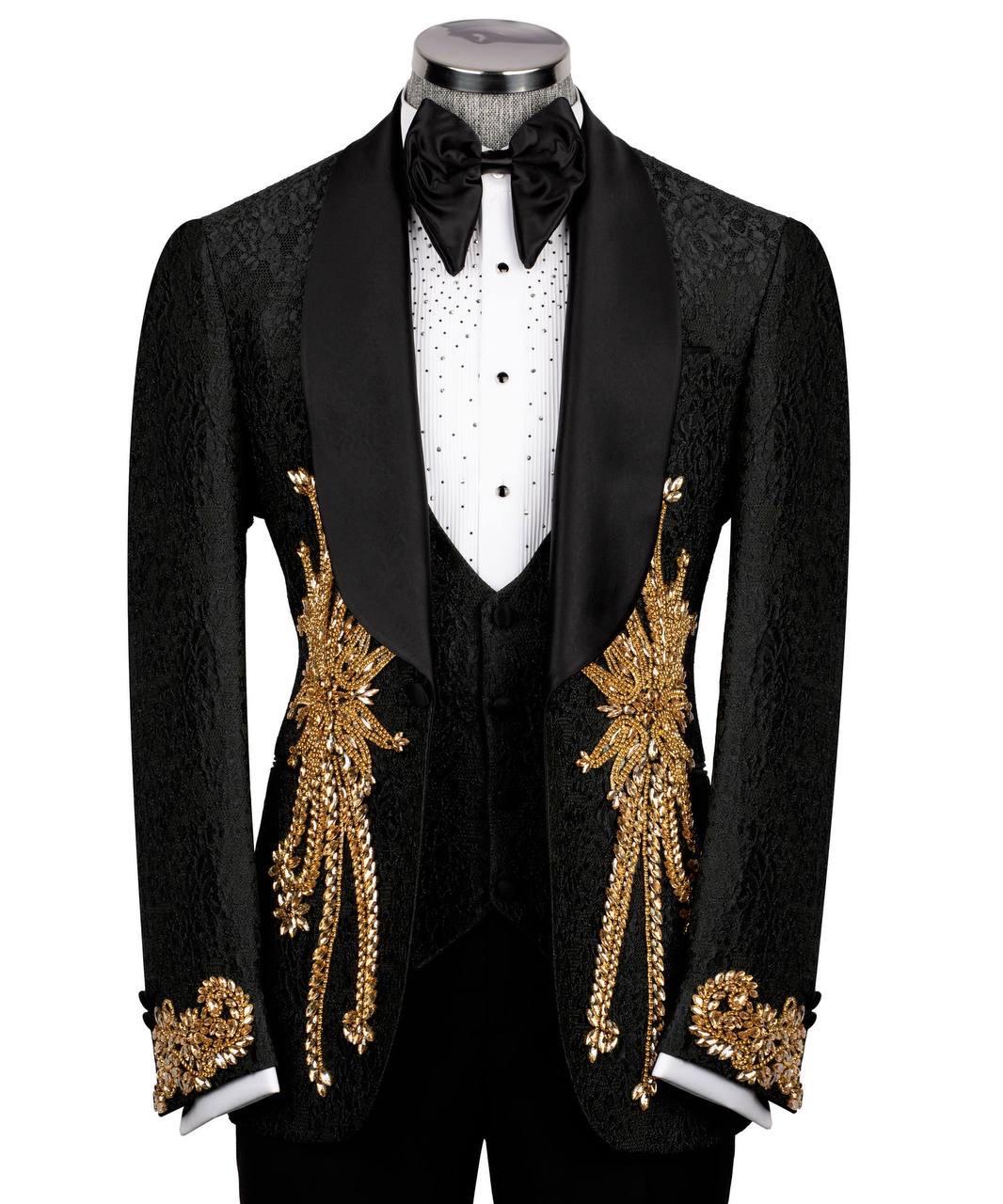 A black tuxedo jacket with ornate gold embroidered leaf motifs and draped gold chain details on the front, displayed on a mannequin with a white polka-dot shirt, black bow tie, and black vest against a plain white background.