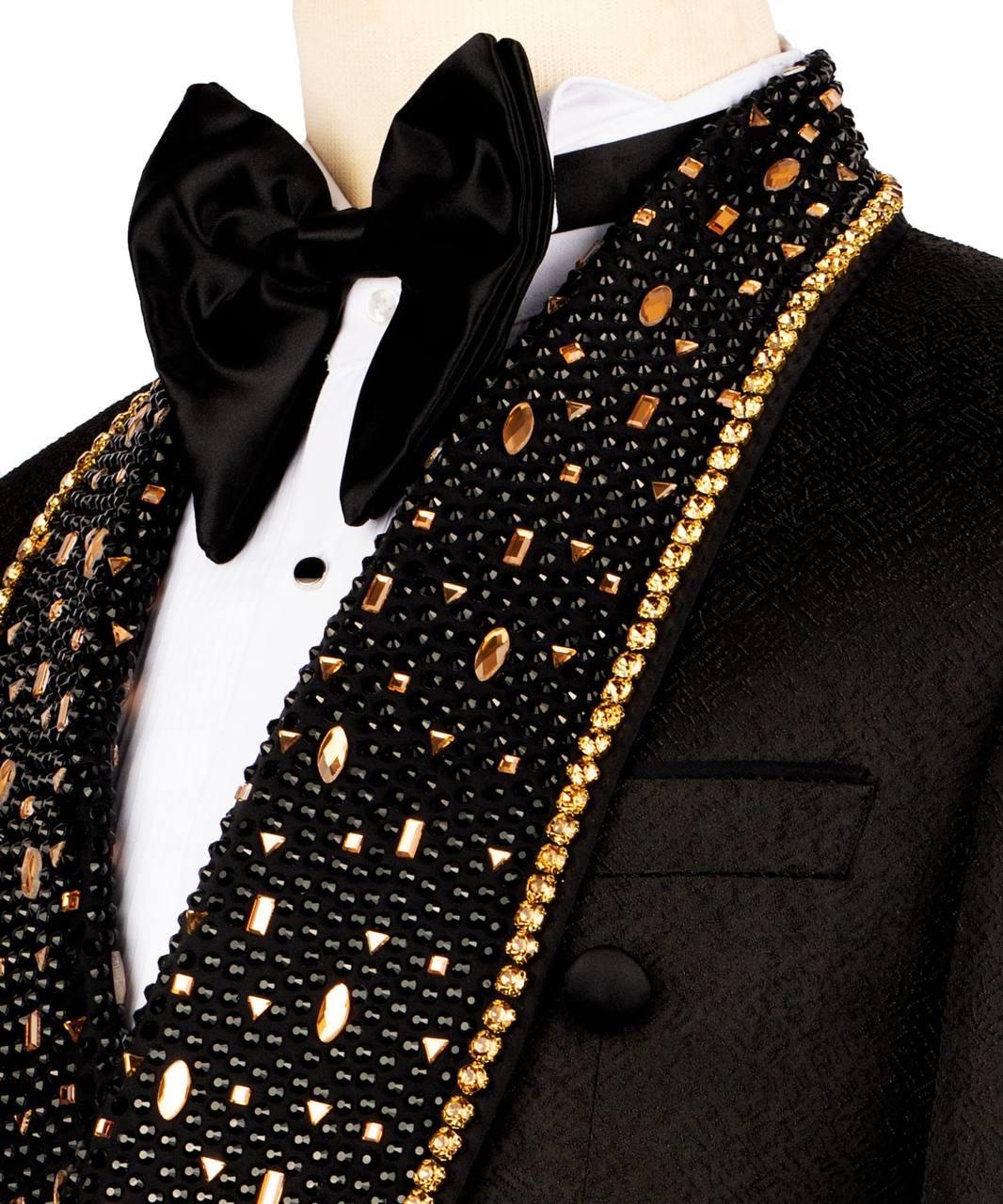 Black tuxedo with gold patterned scarf and black bow tie on a white background