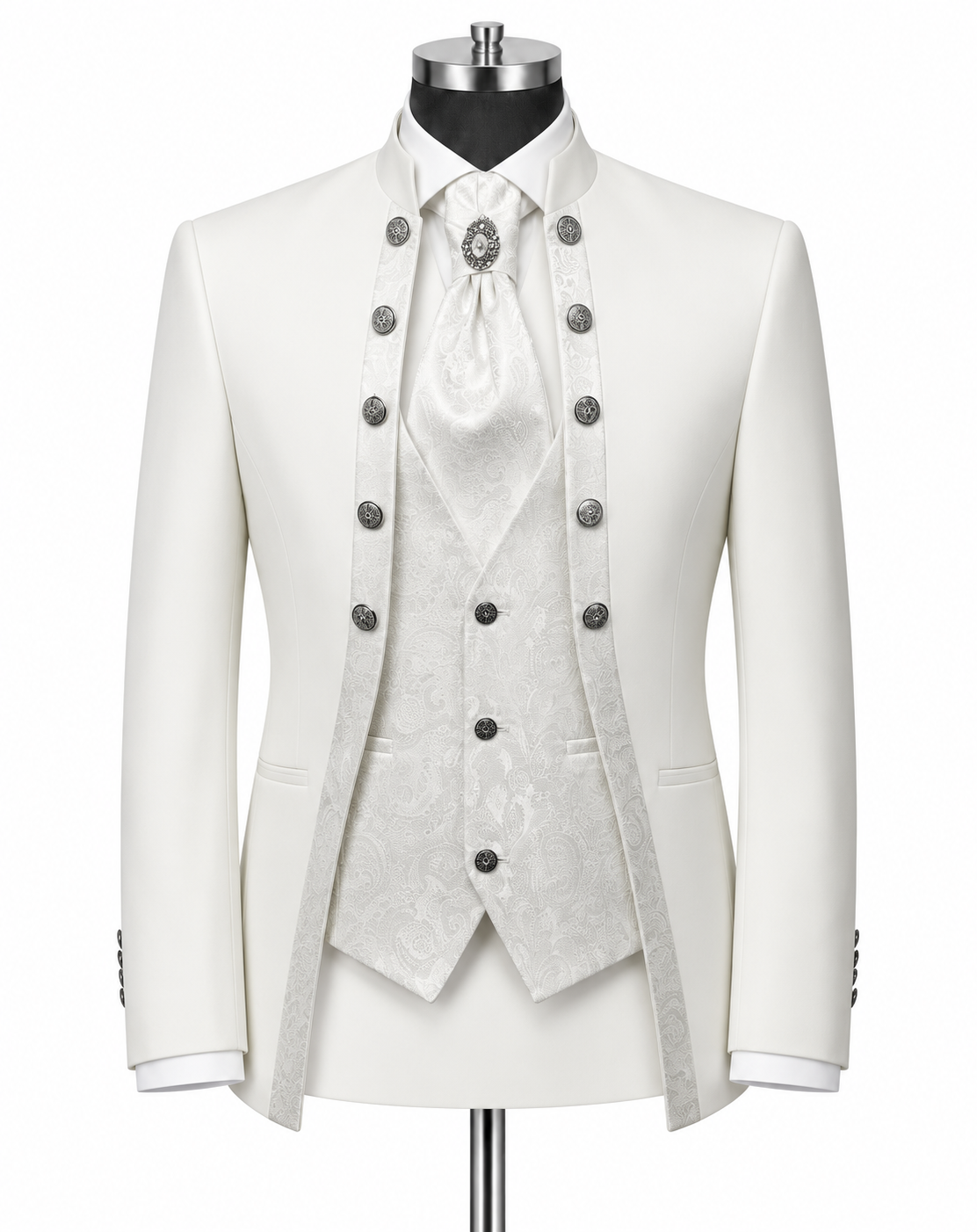 An ornate white formal suit displayed on a mannequin, featuring a double-breasted jacket with silver buttons, a matching patterned waistcoat, white shirt, and a white cravat with a decorative brooch.