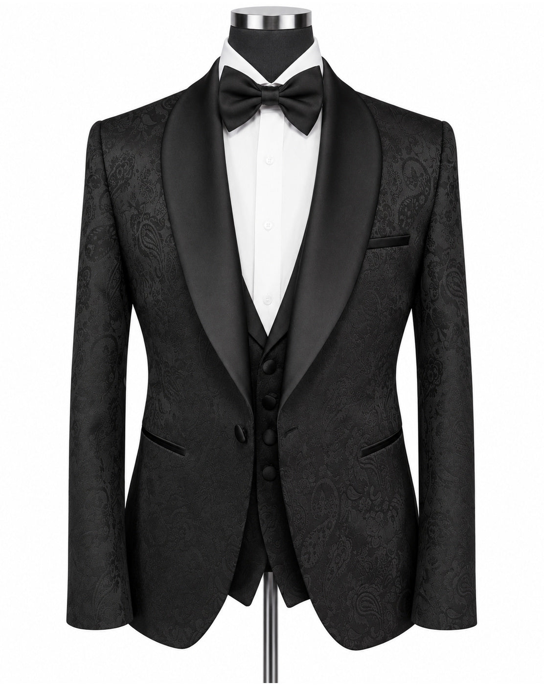 A men's formal tuxedo jacket with black satin shawl collar, black paisley brocade fabric body, paired with a matching black vest, black bow tie, and white dress shirt on a mannequin torso.