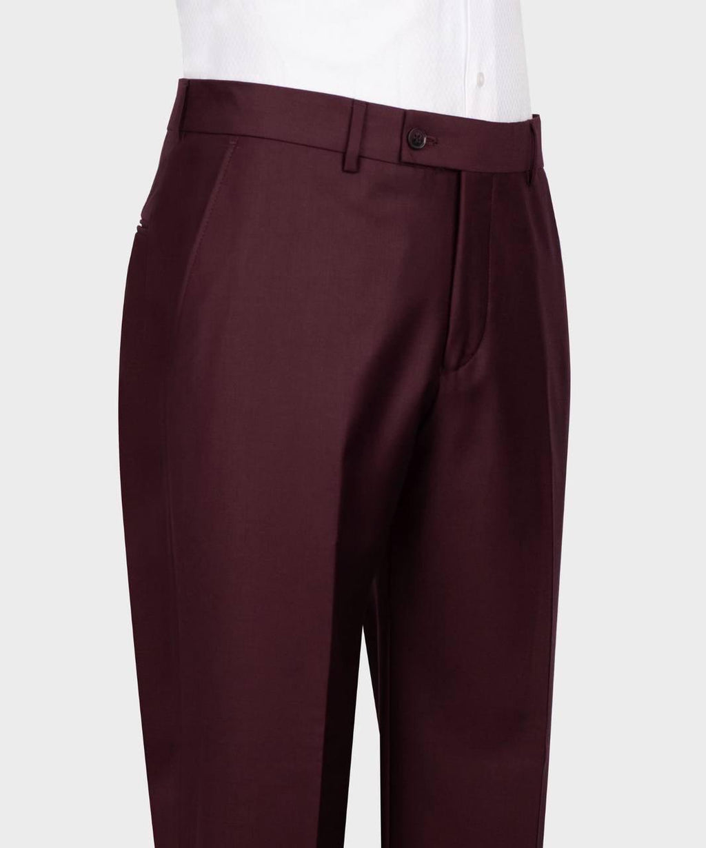 A close-up of a pair of dark burgundy trousers worn by a model, paired with a white collared shirt, shown against a light gray background.