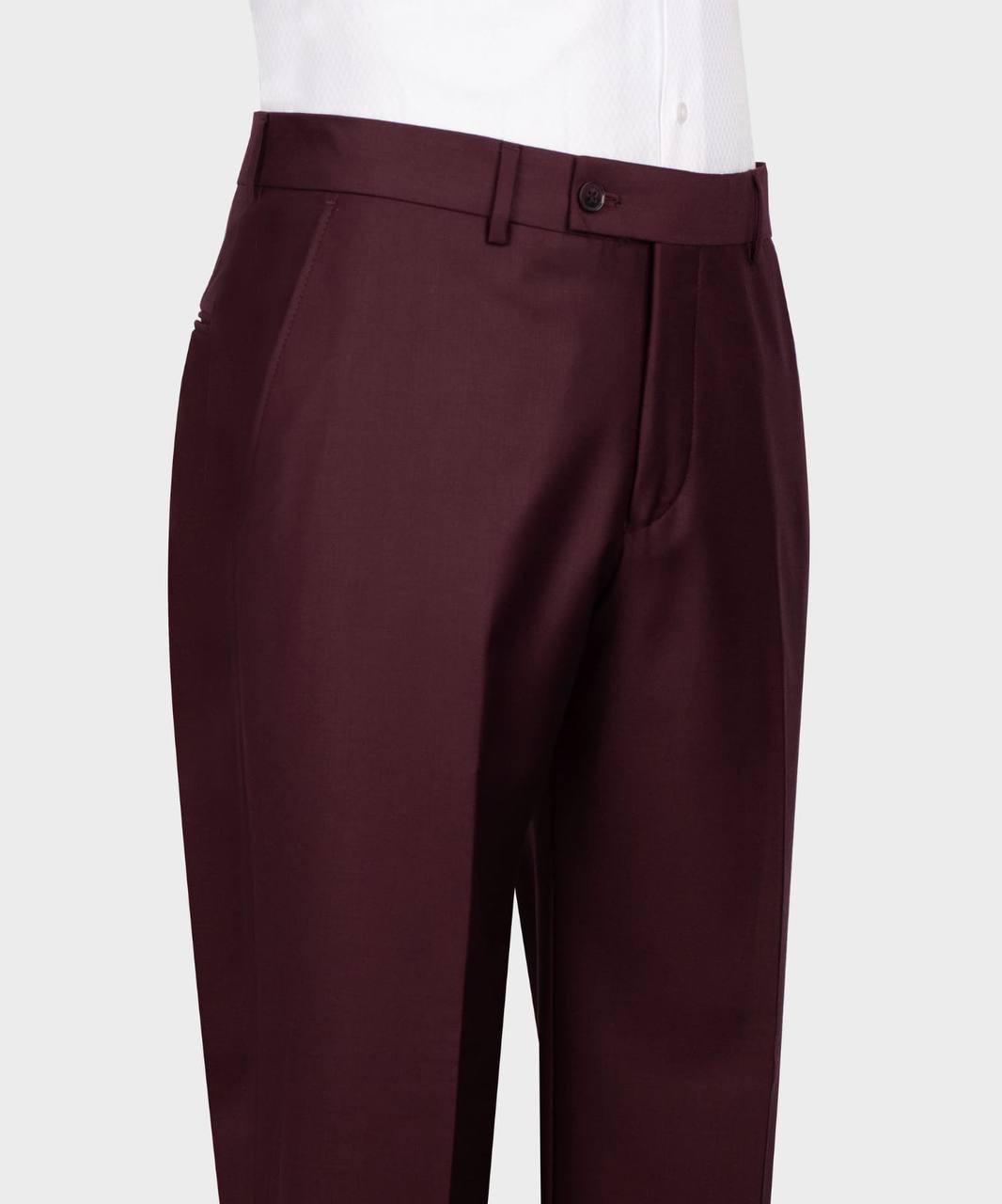 A close-up of a pair of dark burgundy trousers worn by a model, paired with a white collared shirt, shown against a light gray background.