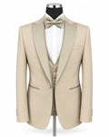 A beige tuxedo jacket with satin peak lapels, displayed on a mannequin with a matching beige bow tie, white dress shirt, and matching beige vest against a plain white background.