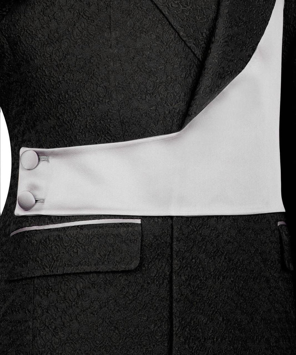 Close-up of a black suit with white lining and buttons on a black background