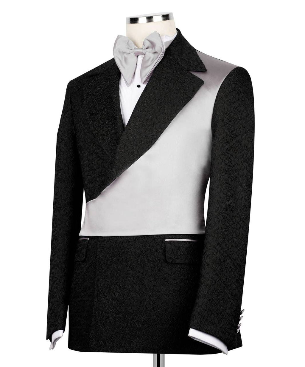 A men's formal tuxedo jacket displayed on a mannequin torso, featuring a black textured fabric body with contrasting smooth light gray panels on the shoulders and lapels, styled with a white shirt and light gray bow tie.