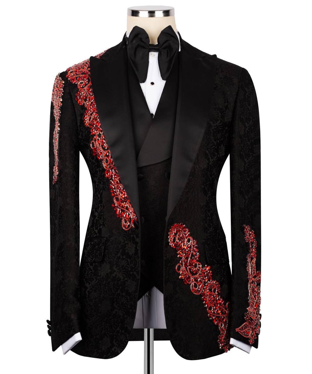 A black tuxedo jacket with ornate red embroidered detailing on the lapels and sleeves, displayed on a mannequin with a black bow tie and white shirt.