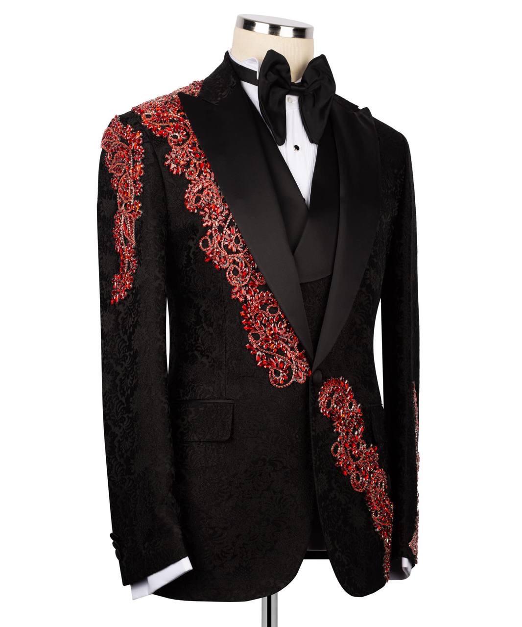 A black tuxedo jacket with ornate red and gold embroidered patterns along the lapels and shoulders, displayed on a mannequin with a black bow tie and white shirt.