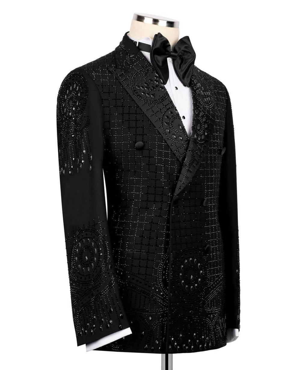 A black double-breasted tuxedo jacket with intricate beadwork and sequin patterns, displayed on a mannequin with a white dress shirt and black bow tie against a white background.