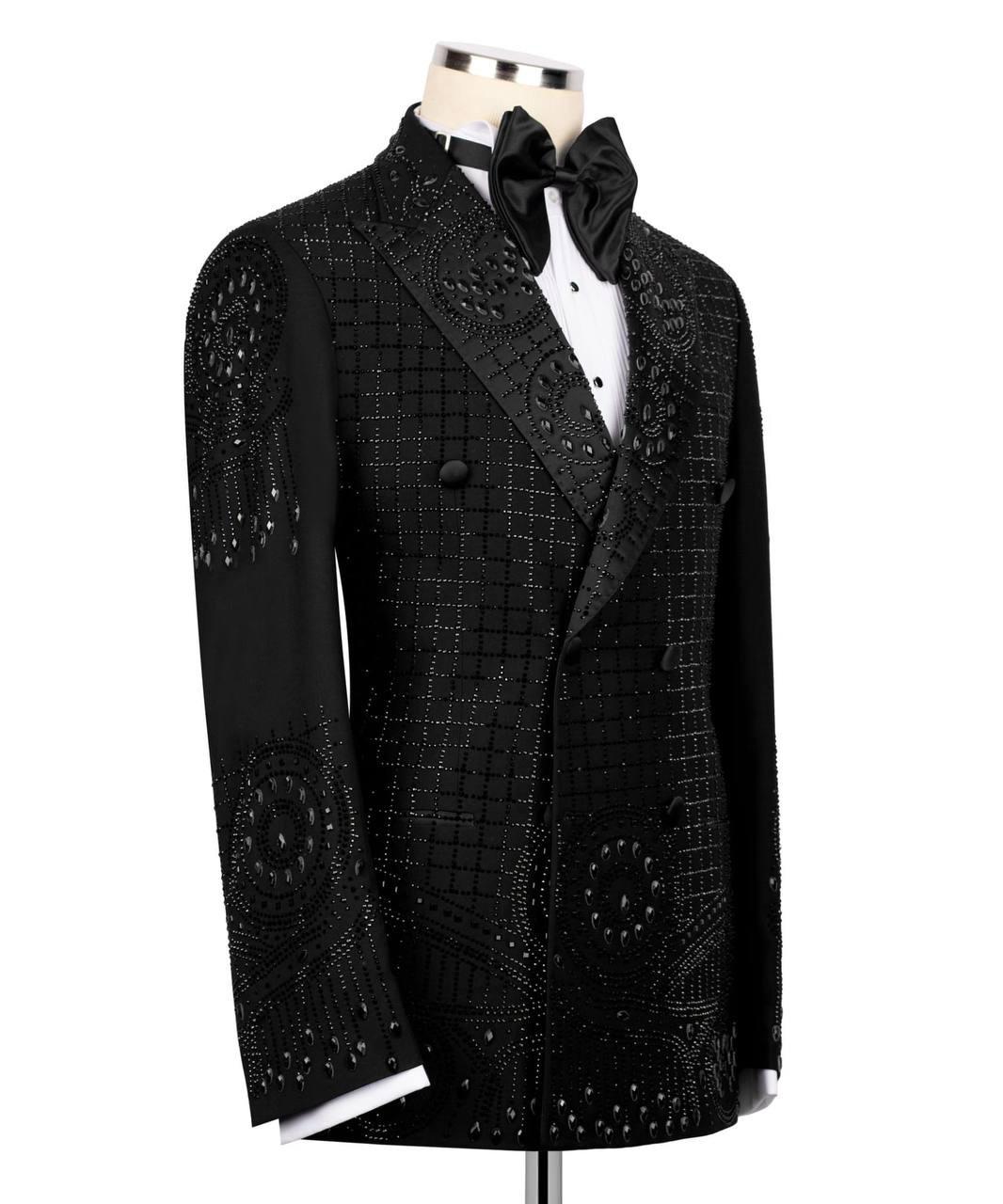 A black double-breasted tuxedo jacket with intricate beadwork and sequin patterns, displayed on a mannequin with a white dress shirt and black bow tie against a white background.
