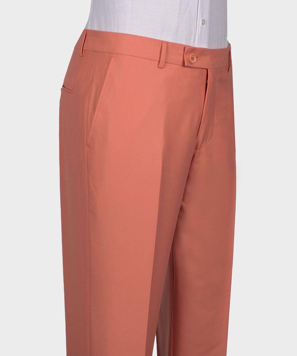 A close-up of a person wearing peach-colored dress pants with a white collared shirt visible at the top, against a light gray studio background.