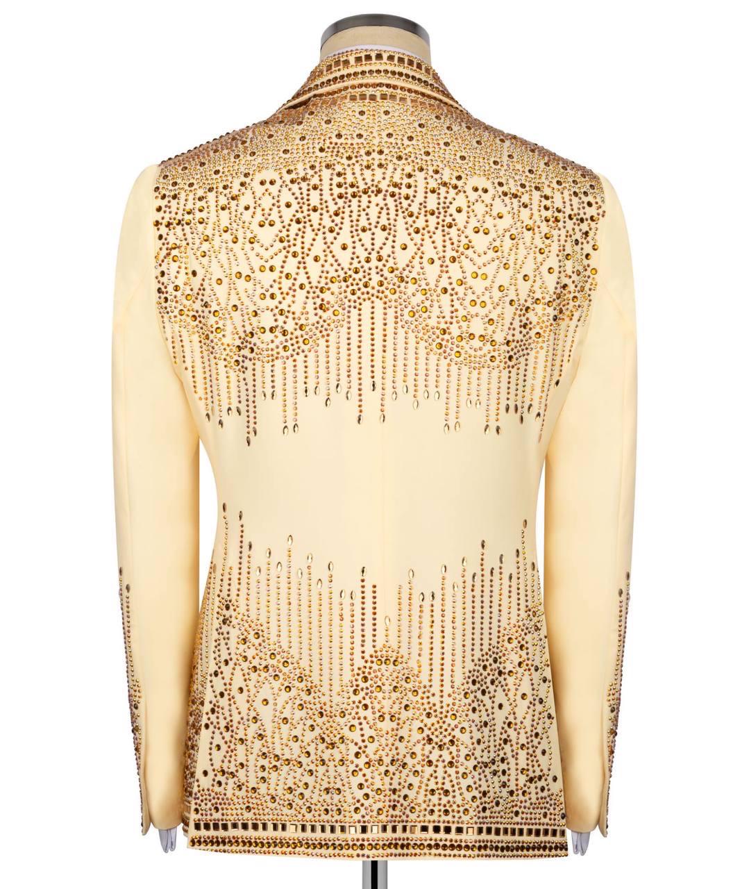 Mannequin wearing a beige shirt with intricate gold beadwork on a white background