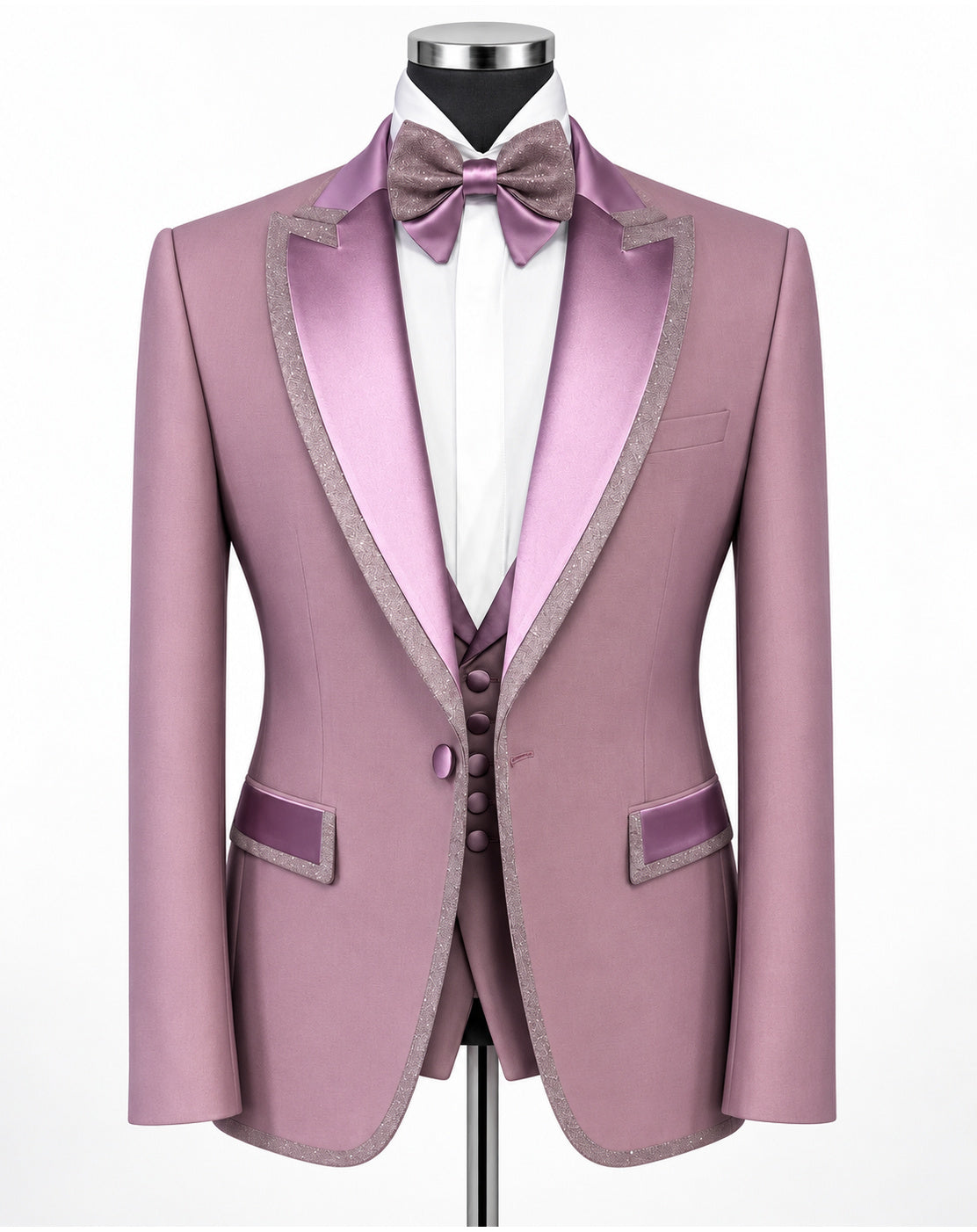 A men's formal suit displayed on a mannequin, featuring a dusty pink blazer with satin lavender lapels and trim, a matching vest, a white dress shirt, a lavender bow tie, and a matching lavender waistcoat.