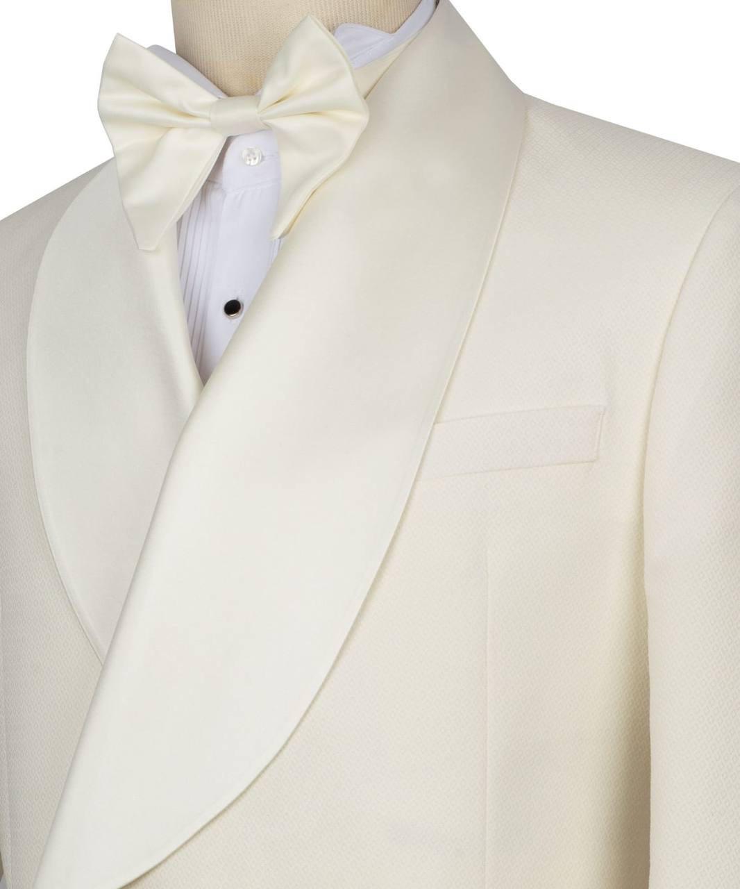 An off-white or cream tuxedo jacket with a satin peak lapel, styled with a matching bow tie and a white pleated dress shirt on a mannequin torso.
