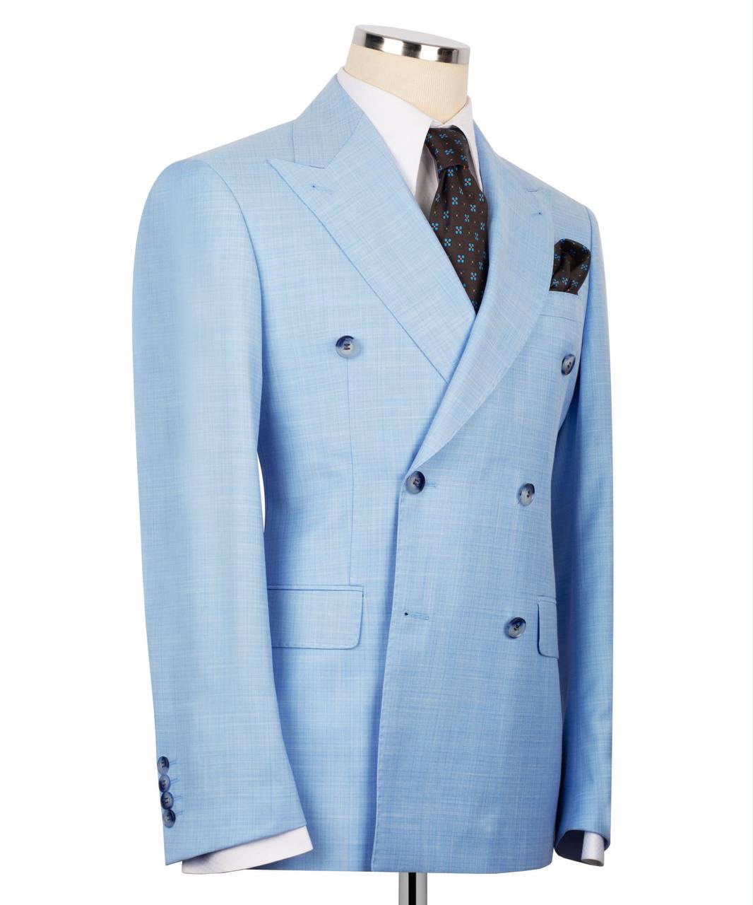 A light blue double-breasted suit jacket displayed on a mannequin torso, styled with a white dress shirt, a dark patterned tie, and a matching pocket square against a plain white background.