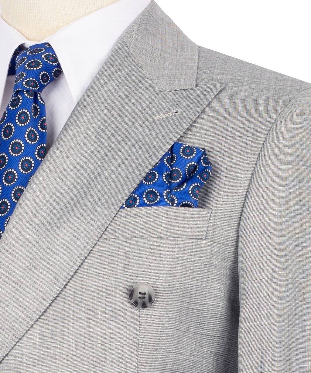 Gray suit jacket with blue patterned tie and pocket square on a mannequin.