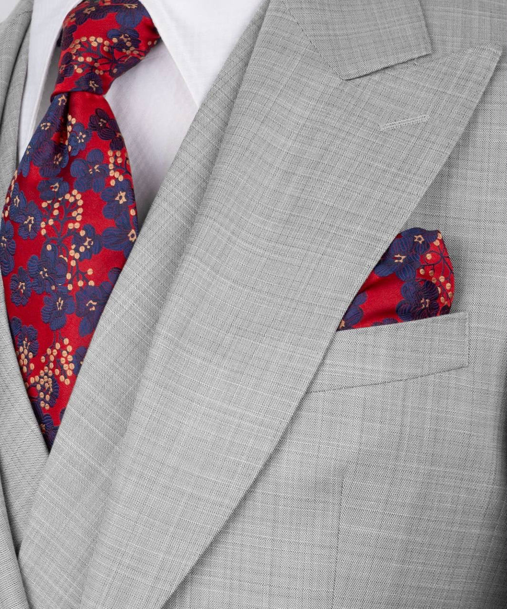 Gray suit with a red and blue patterned tie and pocket square.