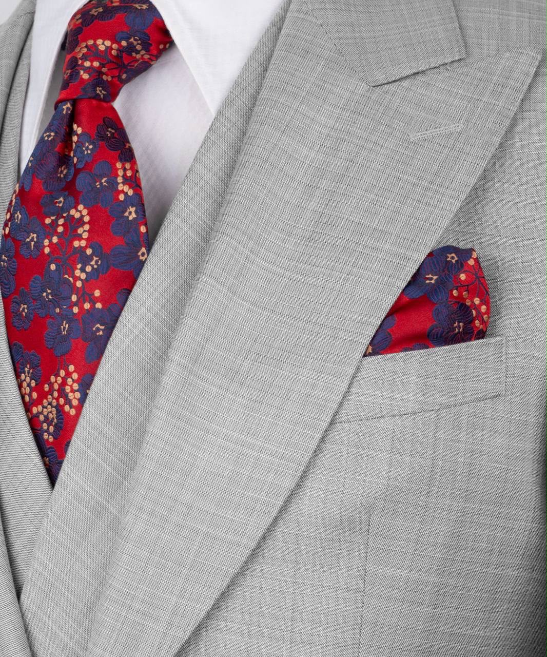 Gray suit with a red and blue patterned tie and pocket square.