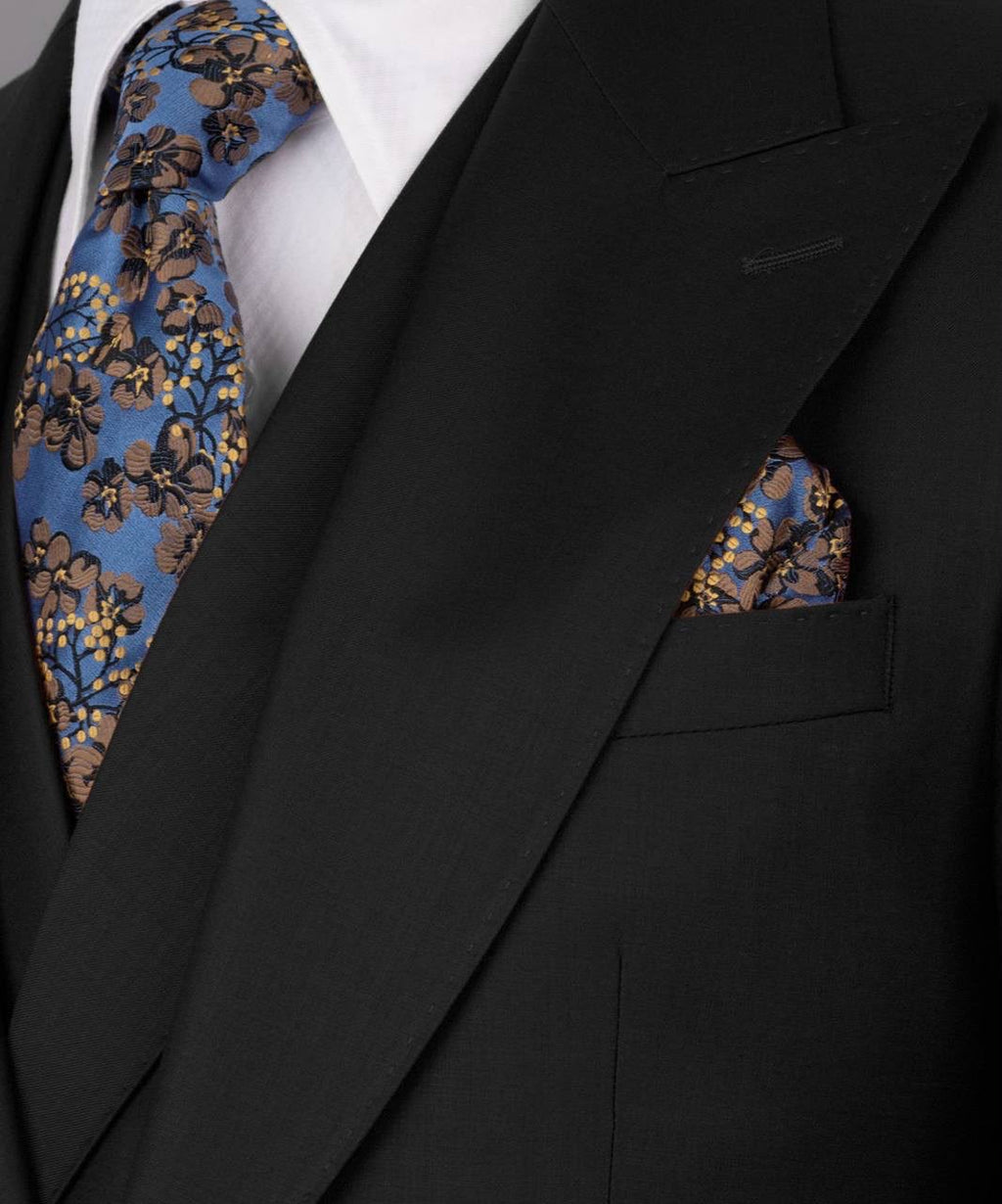 Black suit with floral tie and pocket square on a white background