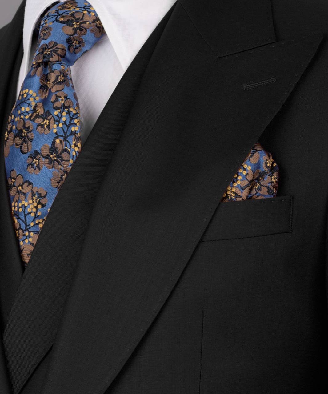 Black suit with floral tie and pocket square on a white background