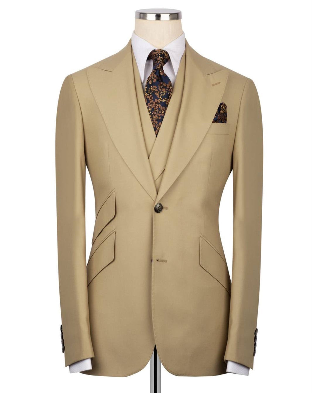 A beige single-breasted suit jacket displayed on a mannequin torso, styled with a white dress shirt, a patterned brown and gold tie, and a matching pocket square against a plain white background.