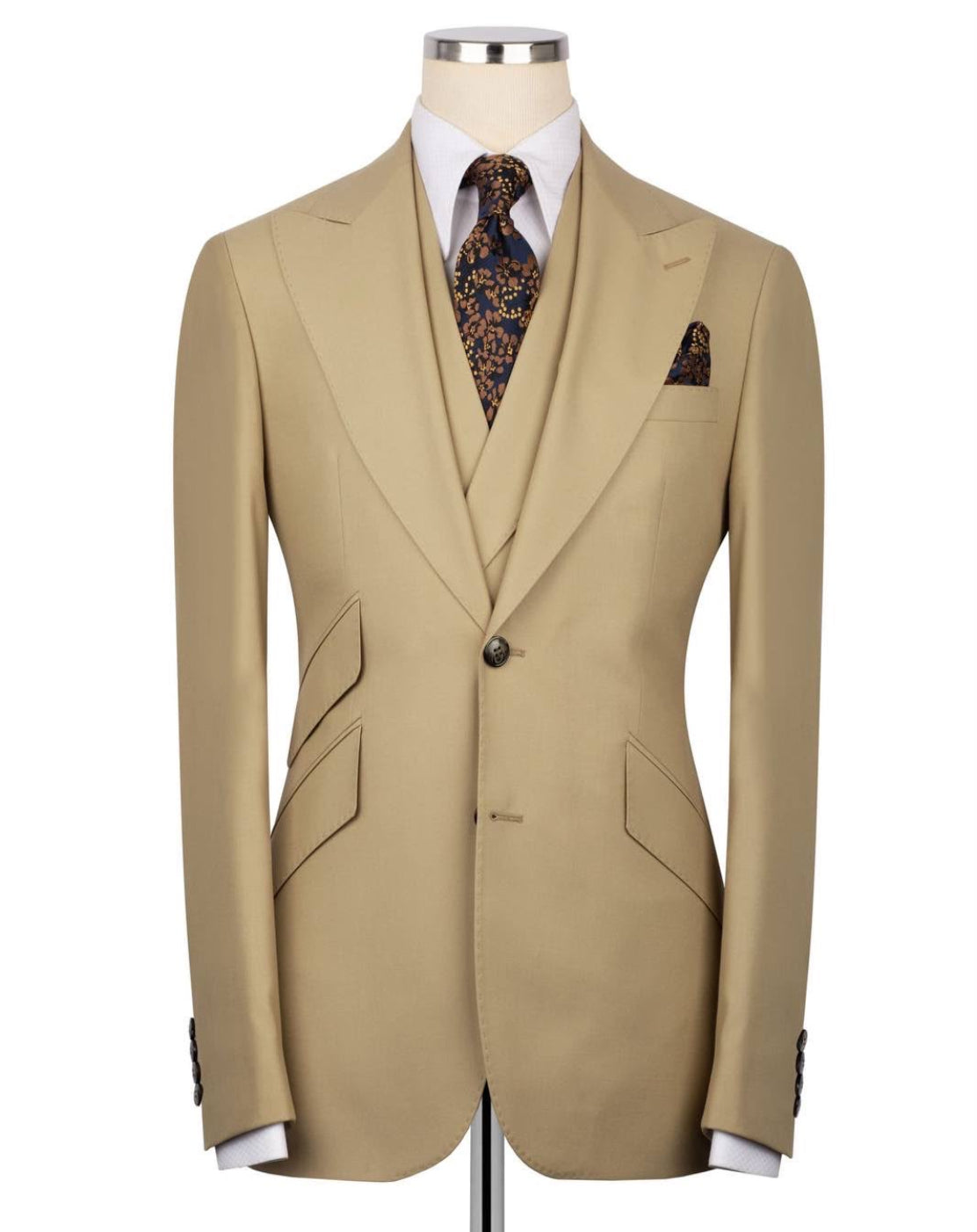 A beige single-breasted suit jacket displayed on a mannequin torso, styled with a white dress shirt, a patterned brown and gold tie, and a matching pocket square against a plain white background.