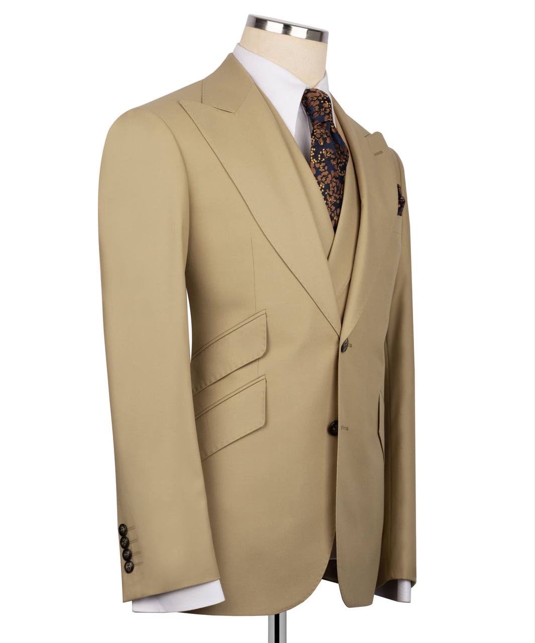 A beige two-piece suit jacket displayed on a mannequin torso with a white dress shirt and a patterned tie, set against a plain white background.