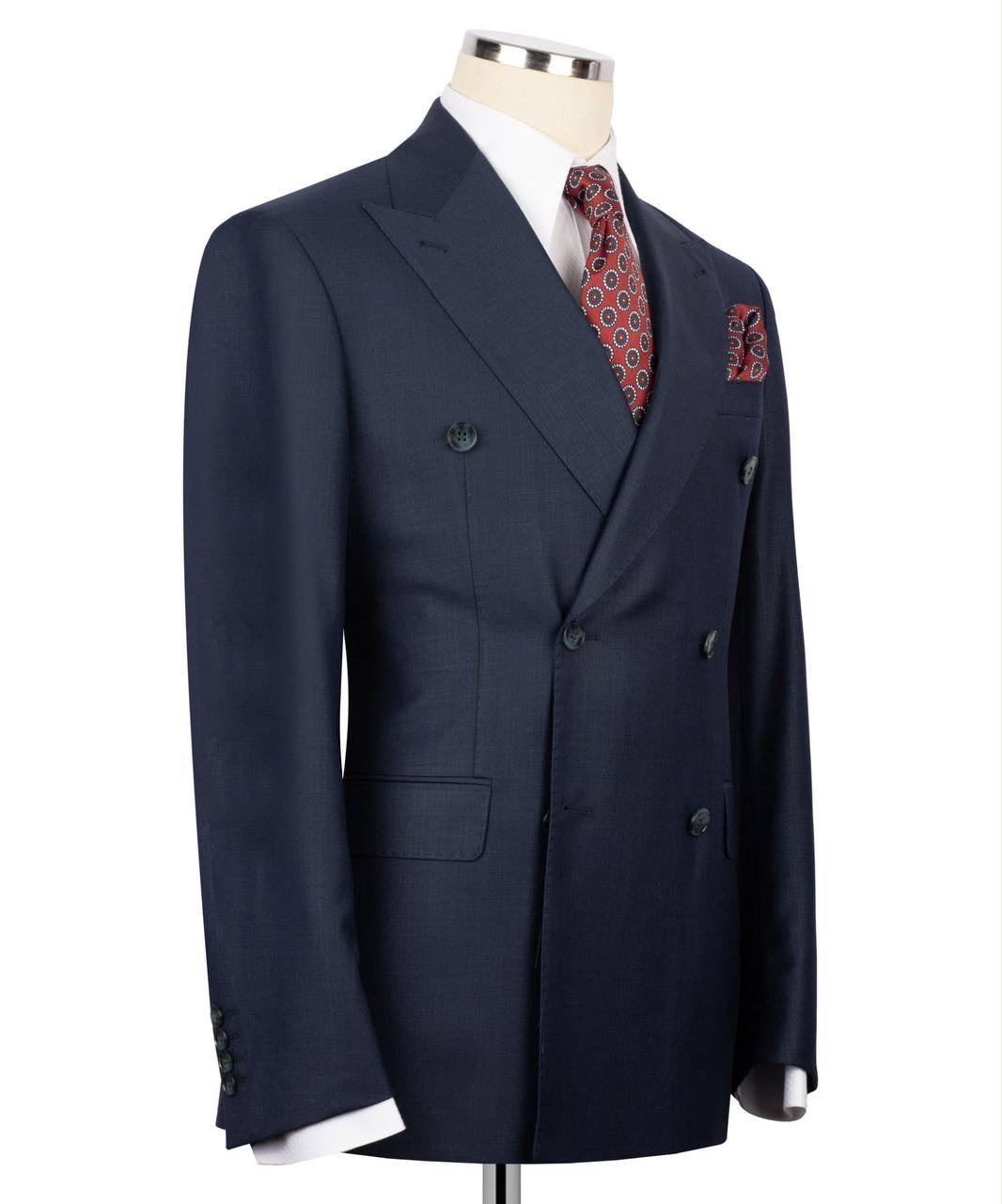 A navy blue double-breasted suit jacket displayed on a mannequin torso, styled with a white dress shirt, a red and gold patterned tie, and a matching pocket square against a plain white background.