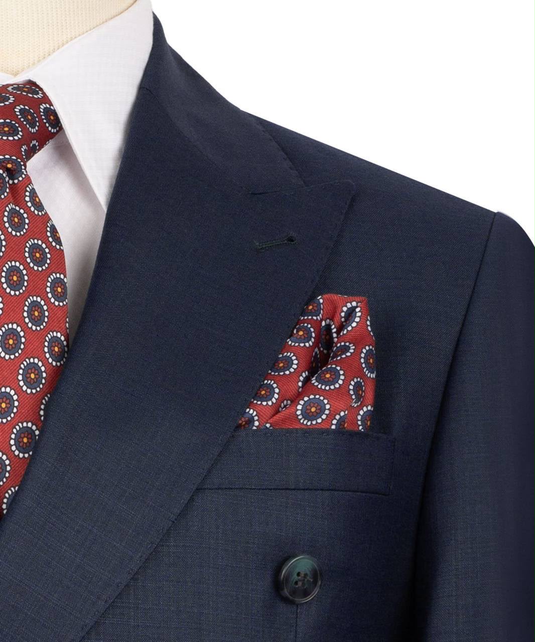 Navy suit with red patterned tie and pocket square on a mannequin.