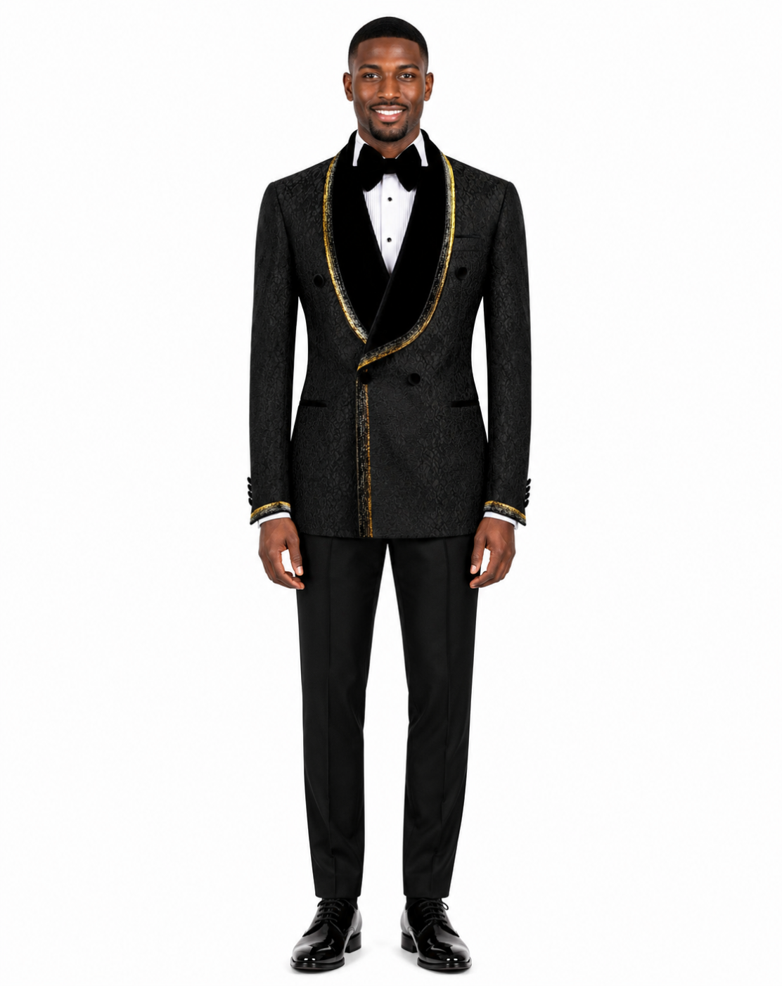 A man modeling a black double-breasted tuxedo jacket with black velvet shawl lapels and gold trim, paired with black trousers, a white dress shirt, and a black bow tie