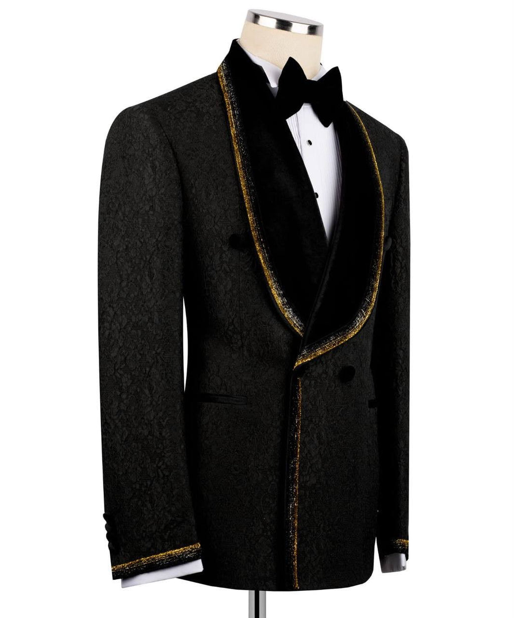 A black double-breasted tuxedo jacket with a textured pattern, black velvet shawl lapels, and gold glitter trim, styled on a mannequin with a white shirt and black bow tie.