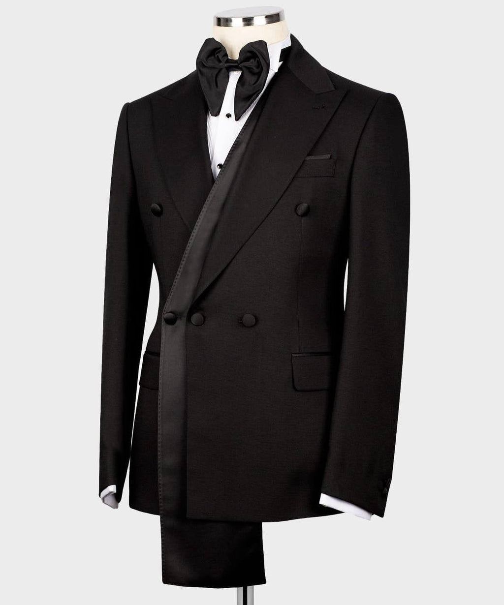 A black double-breasted tuxedo jacket displayed on a mannequin torso, styled with a black bow tie, white dress shirt, and matching black trousers 