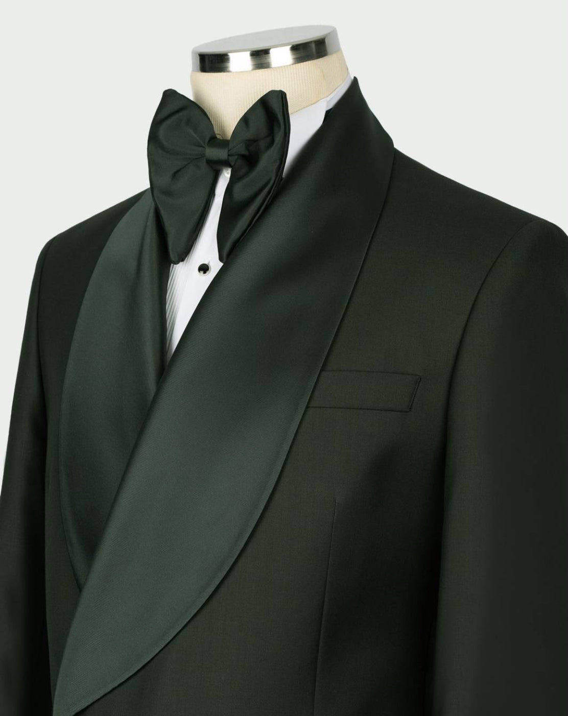 A dark green formal tuxedo jacket with satin peak lapels, styled on a mannequin with a matching dark green bow tie and white dress shirt.