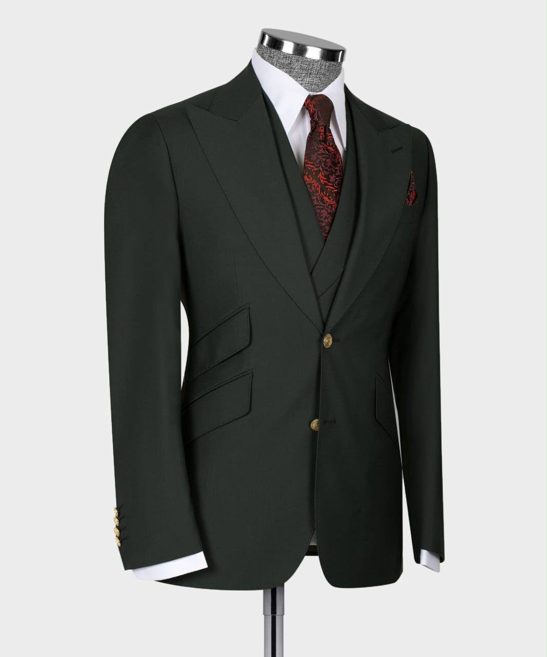 A dark forest green two-button suit jacket displayed on a mannequin torso, styled with a white dress shirt, a red and black patterned tie, and a matching pocket square 