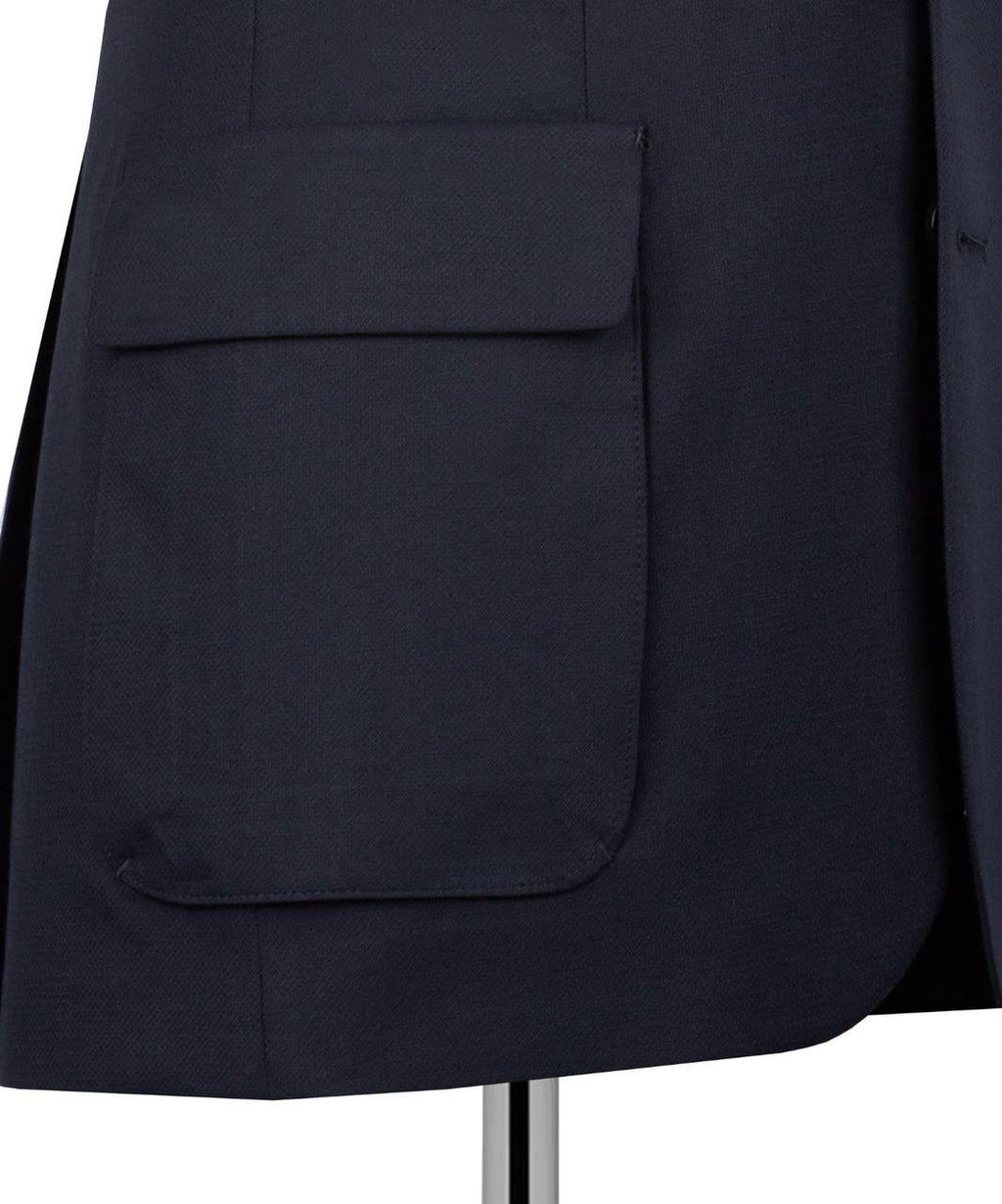 Close-up of a dark navy blue blazer or jacket showing a large front flap pocket on a mannequin or dress form against a white background.