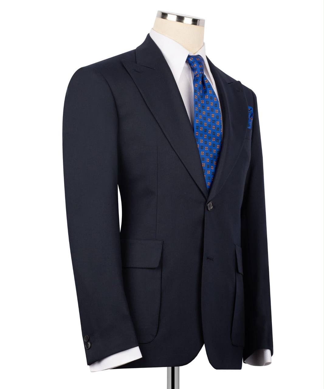A dark navy blue suit jacket displayed on a mannequin torso, styled with a white dress shirt and a blue patterned tie against a plain white background.