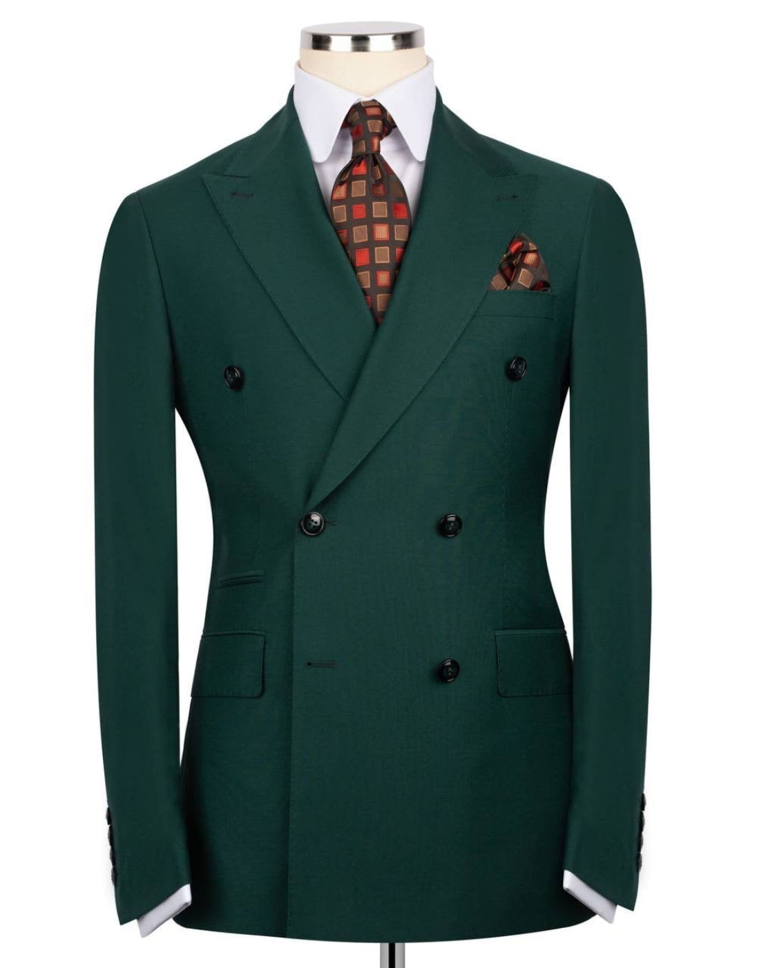 A dark green double-breasted suit jacket displayed on a mannequin torso, styled with a white dress shirt, a red and black patterned tie, and a matching pocket square 