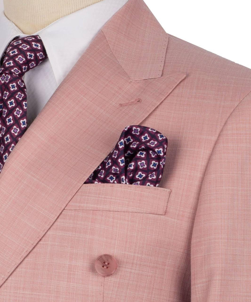 A close-up of a men's suit featuring a dusty pink double-breasted blazer with a subtle grid pattern, styled with a white dress shirt, a patterned burgundy tie, and a matching pocket square.