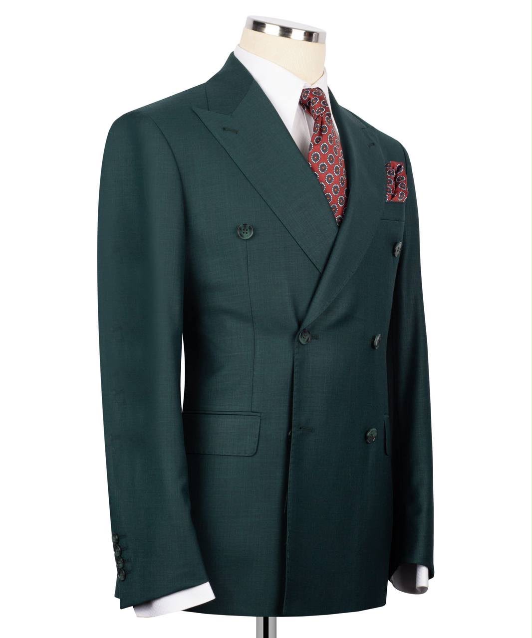 A dark forest green double-breasted suit jacket displayed on a mannequin torso, styled with a white dress shirt, a red and gold patterned tie, and a matching pocket square against a plain white background.