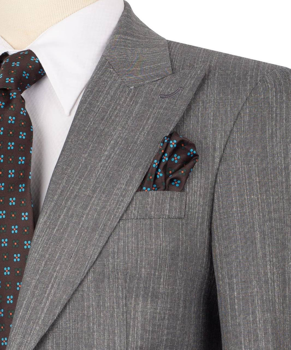 A close-up of a gray pinstripe suit jacket on a mannequin, styled with a white dress shirt, a brown patterned tie, and a matching brown pocket square with blue floral accents.