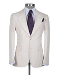 A light cream-colored single-breasted suit jacket displayed on a mannequin torso, styled with a white dress shirt, a purple paisley patterned tie, and a matching pocket square against a light gray background.