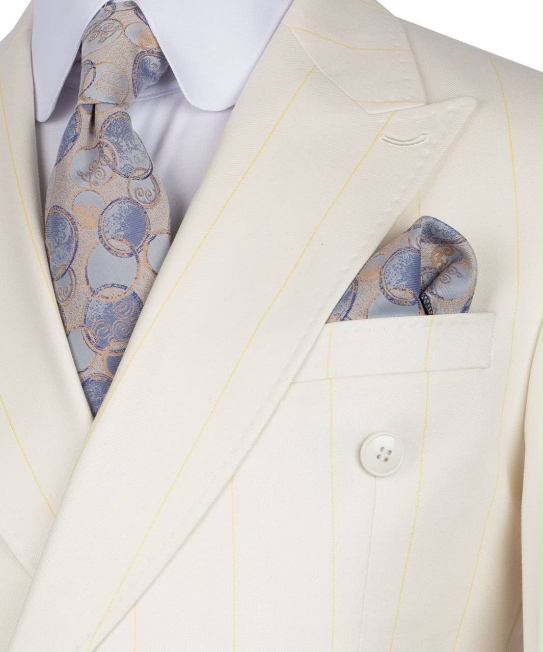 A close-up of a cream-colored double-breasted suit jacket with thin yellow pinstripes, styled with a white dress shirt, a patterned blue and gold tie, and a matching pocket square.